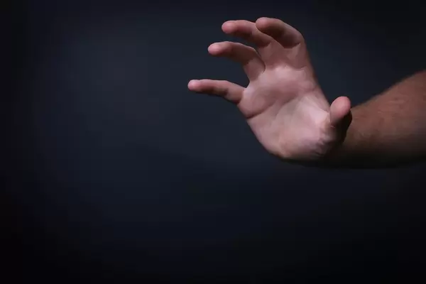 Hand reaching out on black background