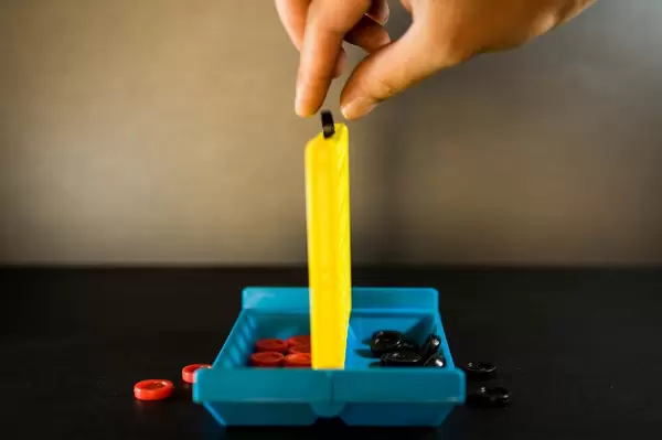 Hand releasing a black connect four token
