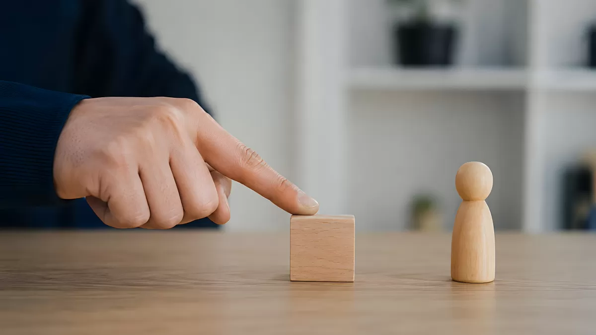 Hand schiebt Holzklotz zu Holzfigur auf Tisch