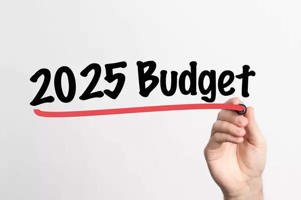 Hand schreibt Budget für 2025 auf ein Whiteboard