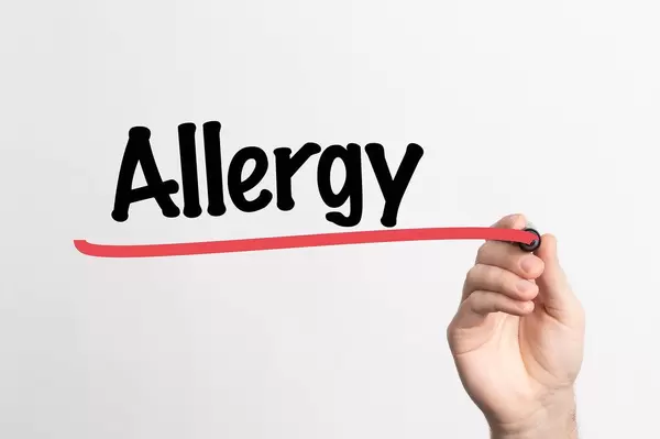 Hand schreibt das Wort "Allergie" auf ein Whiteboard
