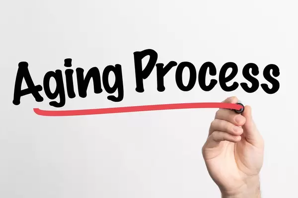 Hand schreibt das Wort "Alterungsprozess" auf ein Whiteboard