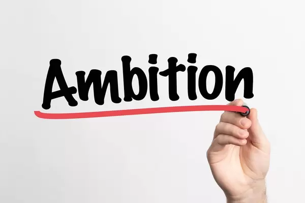 Hand schreibt das Wort "Ambition" auf ein Whiteboard