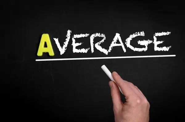 Hand schreibt das Wort "Average" - Durchschnitt - mit Kreide auf eine schwarze Tafel