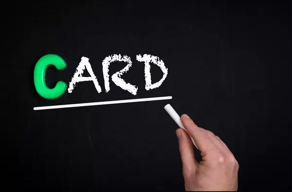 Hand schreibt das Wort "Card" - Karte - mit Kreide auf eine schwarze Tafel
