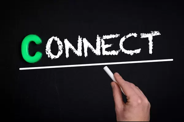 Hand schreibt das Wort "Connect" - verbinden - mit Kreide auf eine schwarze Tafel