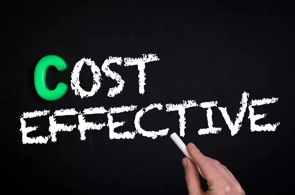 Hand schreibt das Wort "Cost Effective" - Kosteneffizient - mit Kreide auf eine schwarze Tafel
