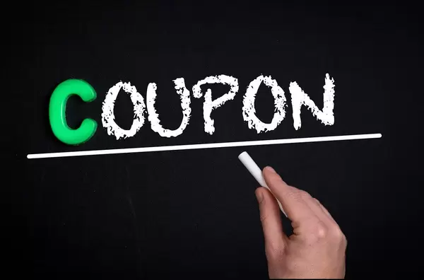 Hand schreibt das Wort "Coupon" mit Kreide auf eine schwarze Tafel