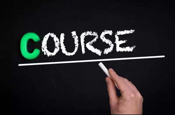 Hand schreibt das Wort "Course" - Kurs / Strecke - mit Kreide auf eine schwarze Tafel