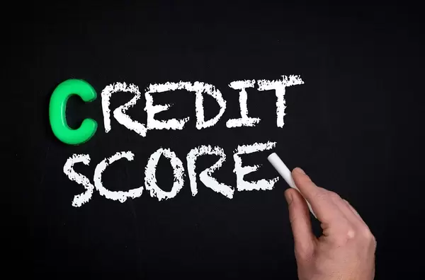 Hand schreibt das Wort "Credit Score" - Bonität / Kreditwürdigkeit - mit Kreide auf eine schwarze Tafel