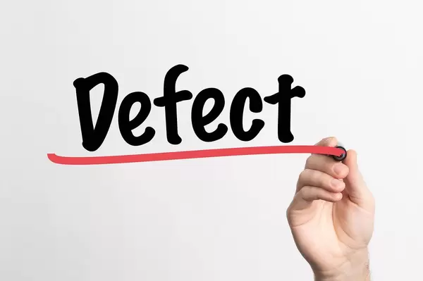 Hand schreibt das Wort "Defekt" auf ein Whiteboard