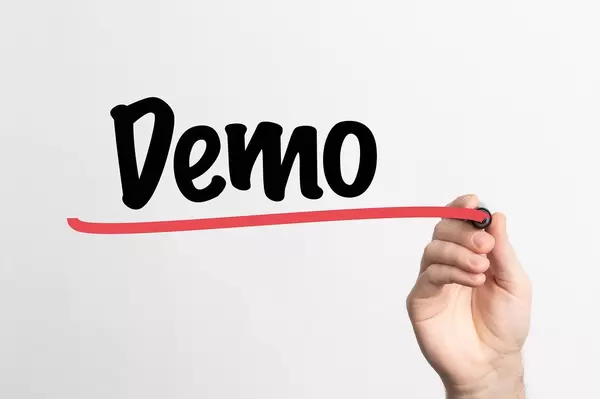 Hand schreibt das Wort "Demo" auf ein Whiteboard