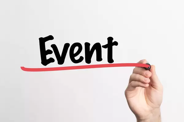 Hand schreibt das Wort "Event / Veranstaltung" auf ein Whiteboard