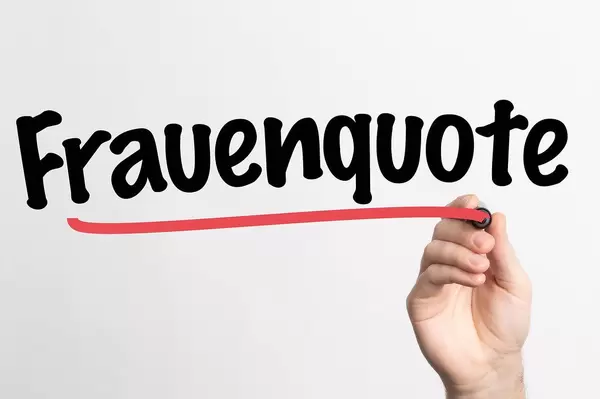 Hand schreibt das Wort "Frauenquote" auf ein Whiteboard