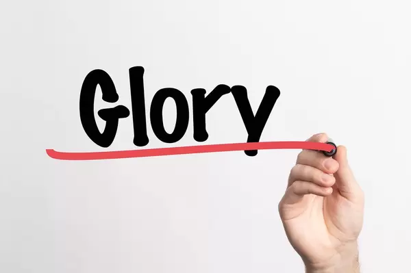 Hand schreibt das Wort "Herrlichkeit / triumphieren" auf ein Whiteboard