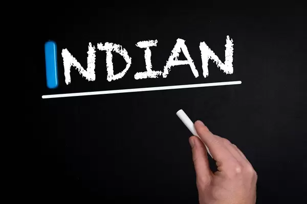 Hand schreibt das Wort "Indian" - Indisch - mit Kreide auf eine schwarze Tafel