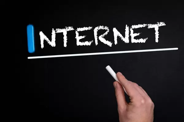 Hand schreibt das Wort "Internet" mit Kreide auf eine schwarze Tafel