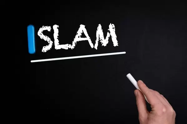 Hand schreibt das Wort "Islam" mit Kreide auf eine schwarze Tafel