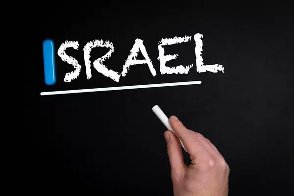 Hand schreibt das Wort "Israel" mit Kreide auf eine schwarze Tafel