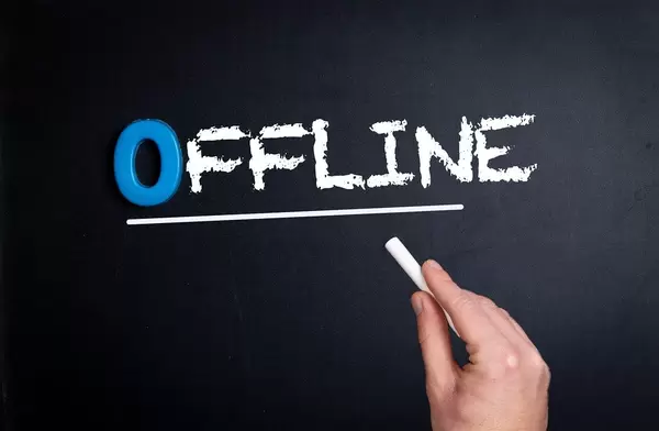 Hand schreibt das Wort "Offline"  mit Kreide auf eine schwarze Tafel