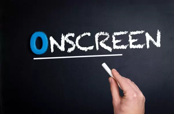 Hand schreibt das Wort "Onscreen" - Auf dem Bildschirm - mit Kreide auf eine schwarze Tafel