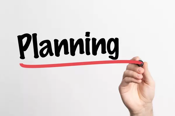 Hand schreibt das Wort "Planung / planen" auf ein Whiteboard