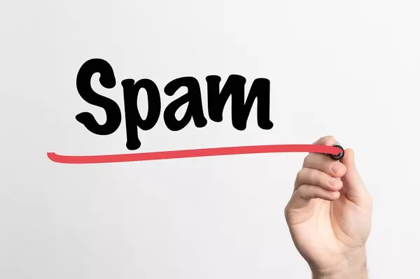 Hand schreibt das Wort "Spam" auf ein Whiteboard