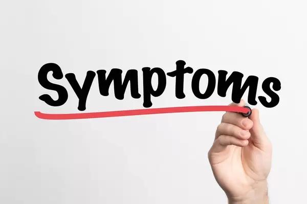 Hand schreibt das Wort "Symptome" auf ein Whiteboard