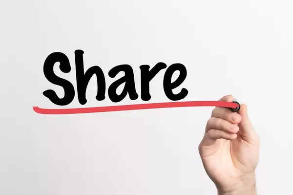 Hand schreibt das Wort "teilen" auf ein Whiteboard