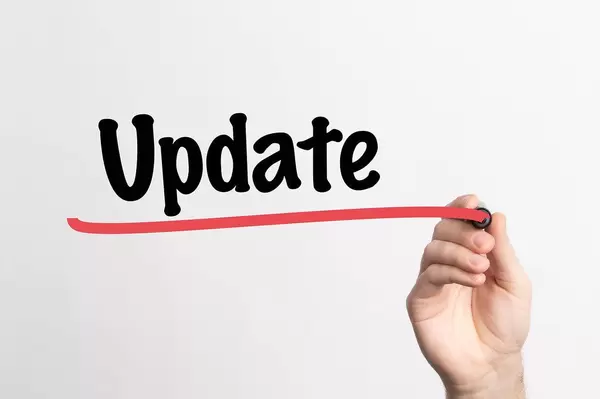 Hand schreibt das Wort "Update" auf ein Whiteboard