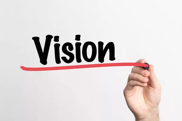 Hand schreibt das Wort "Vision" auf ein Whiteboard