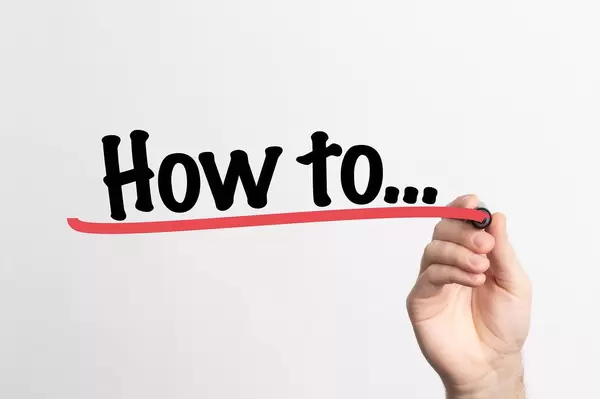 Hand schreibt das Wort "Wie ... " auf ein Whiteboard