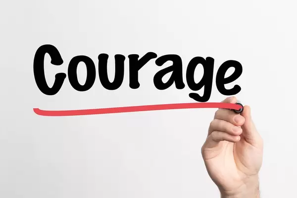 Hand schreibt das Wort "Zivilcourage / Mut" auf ein Whiteboard