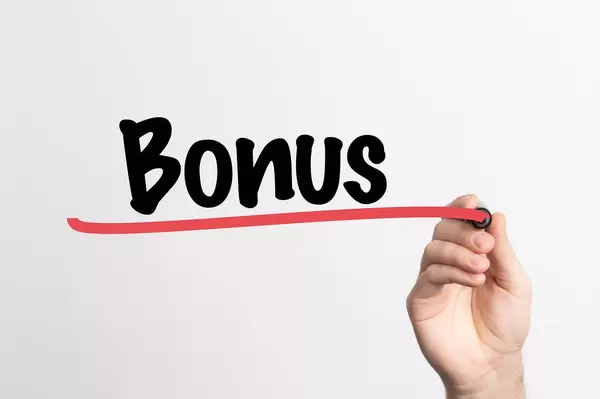 Hand schreibt "Bonus" auf ein Whiteboard