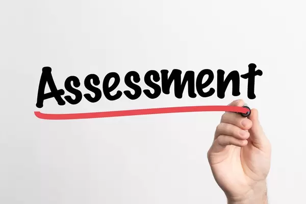 Hand schreibt "Einschätzung / Beuurteilung" auf ein Whiteboard
