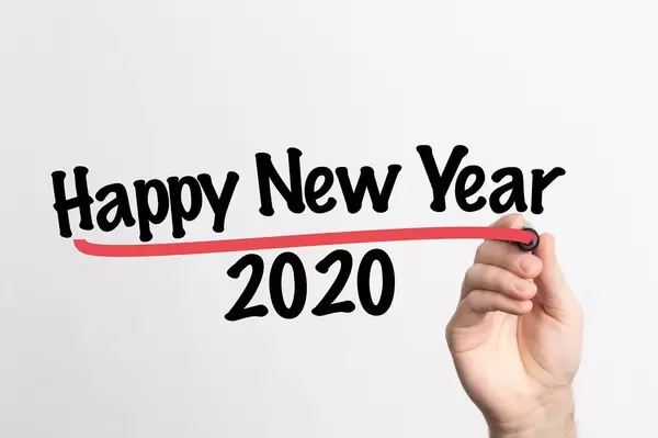Hand schreibt  "Frohes neues Jahr 2020" auf ein Whiteboard