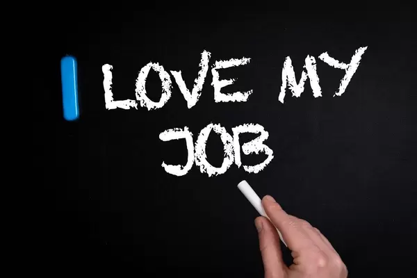 Hand schreibt "I love my job" - Ich liebe meinen Beruf - mit Kreide auf eine schwarze Tafel