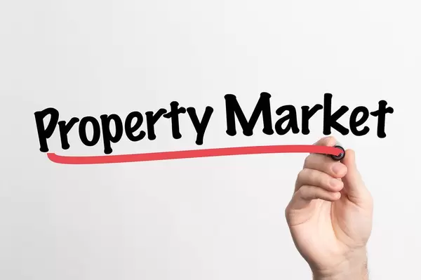 Hand schreibt "Immobilienmarkt" auf ein Whiteboard