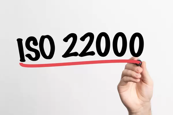 Hand schreibt "ISO 22000" auf ein Whiteboard