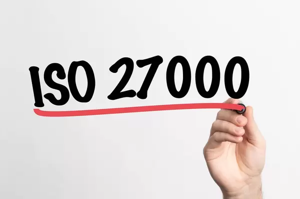 Hand schreibt "ISO 27000" auf ein Whiteboard