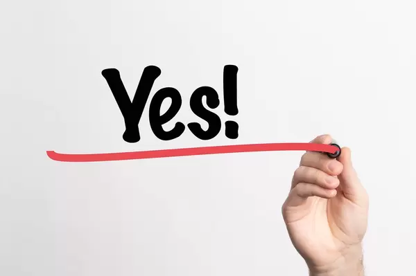 Hand schreibt "Ja!" auf ein Whiteboard