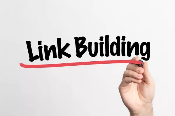 Hand schreibt "Linkbuilding / Linkaufbau" auf ein Whiteboard
