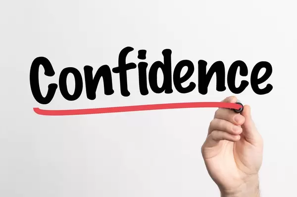 Hand schreibt "Selbstvertrauen / Zuversicht" auf ein Whiteboard
