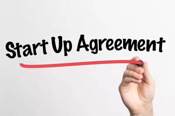 Hand schreibt "Start-up Vereinbarung" auf ein Whiteboard