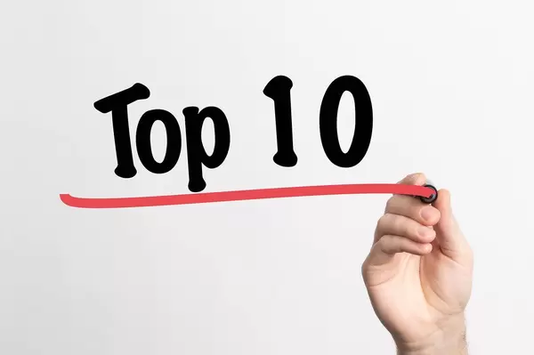 Hand schreibt  "TOP 10 / die besten 10" auf ein Whiteboard