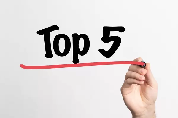 Hand schreibt "TOP 5 / die besten 5" auf ein Whiteboard