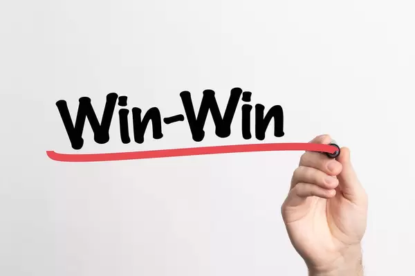 Hand schreibt "Win-Win" auf ein Whiteboard