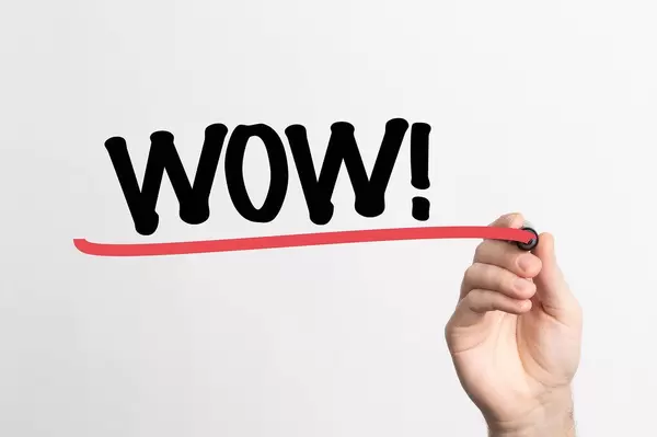 Hand schreibt "wow!" auf ein Whiteboard