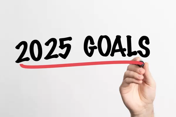 Hand schreibt Ziele für 2025 auf ein Whiteboard