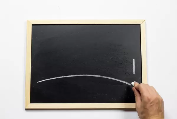 Hand schriebt mit Kreide auf einer Tafel